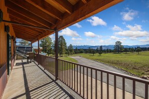 Una terraza de madera con vistas a un campo verde y montañas.