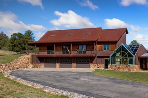 A two-story house with a stone foundation, a large garage, and a covered porch. - New! Private 40-Acre Retreat | Sneffels Mtn Views | 10 Minutes to Ridgway (Ridgway)