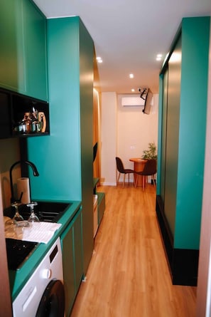 Una cocina compacta con suelo de madera, un comedor con dos sillas y una pequeña mesa.