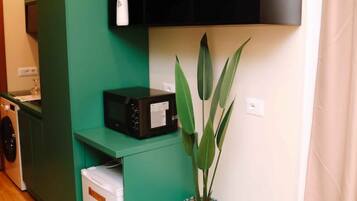 A compact kitchen with green cabinetry, a microwave, and a potted plant.