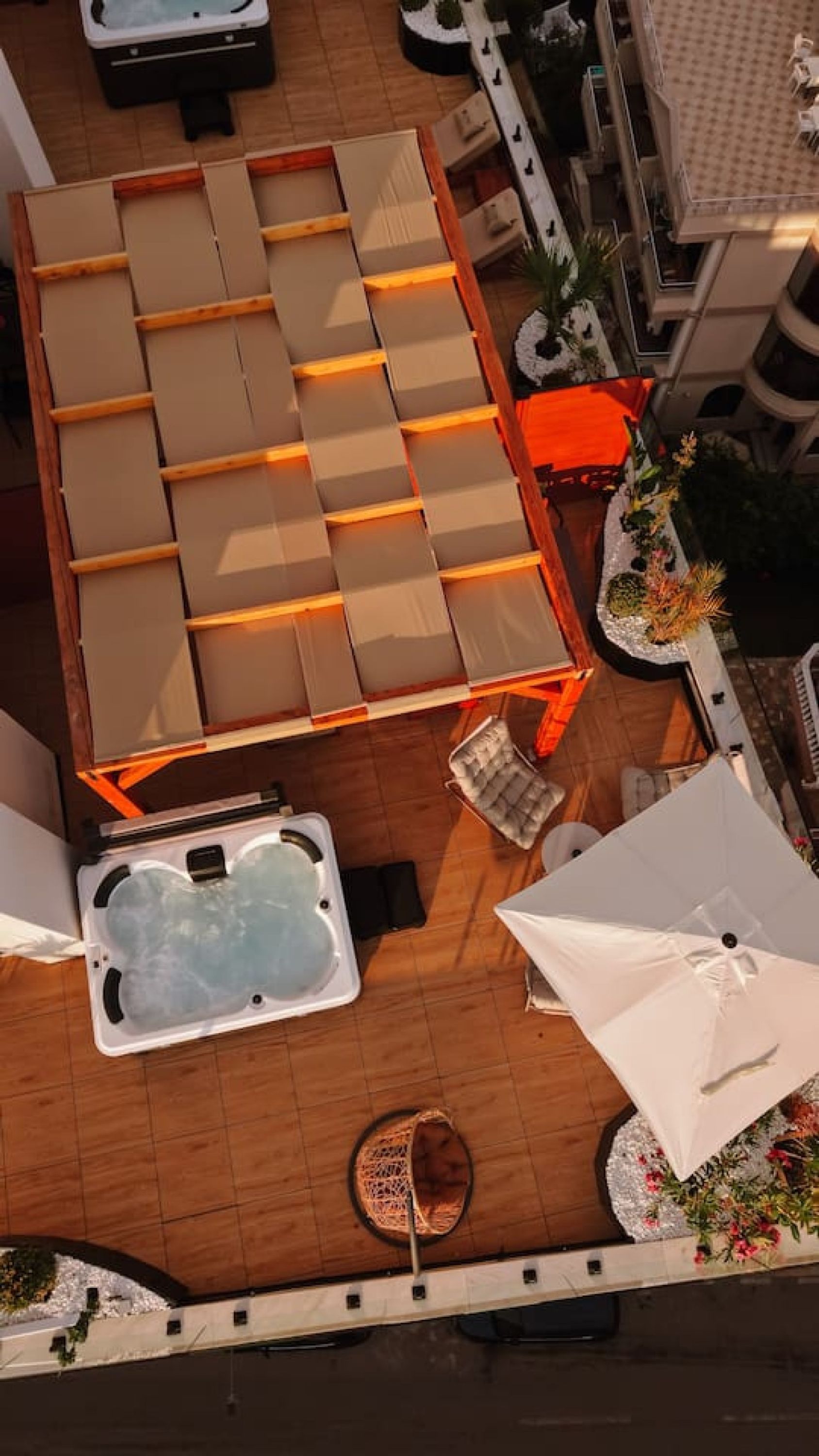 A rooftop terrace with a sun lounger, a hot tub, and a covered seating area.