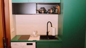 A compact kitchen with a washing machine, a sink, and a countertop with kitchen utensils.