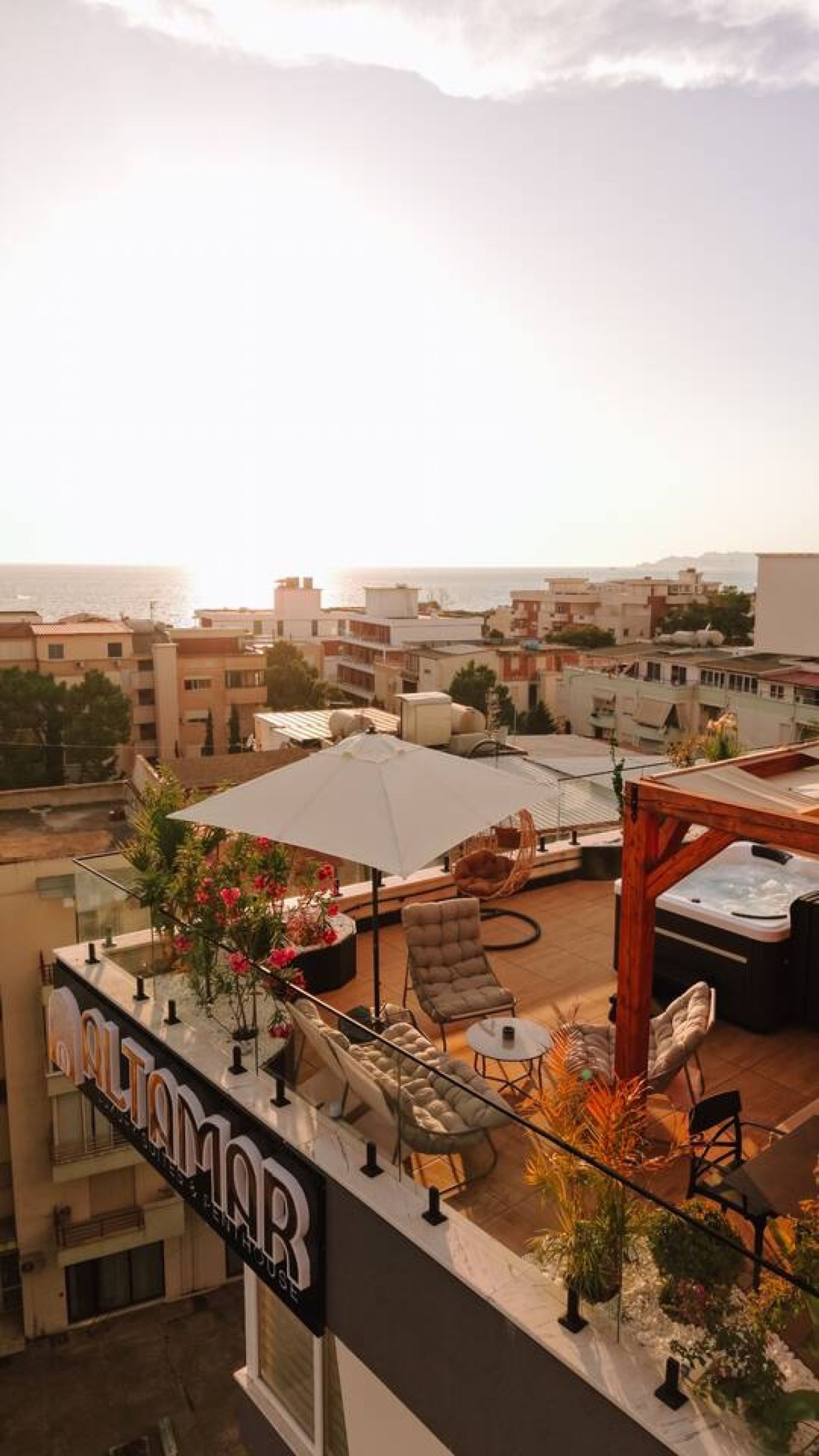 A rooftop terrace with outdoor seating, a hot tub, and a view of the cityscape.