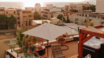 A rooftop terrace with outdoor seating, a hot tub, and a view of the cityscape.