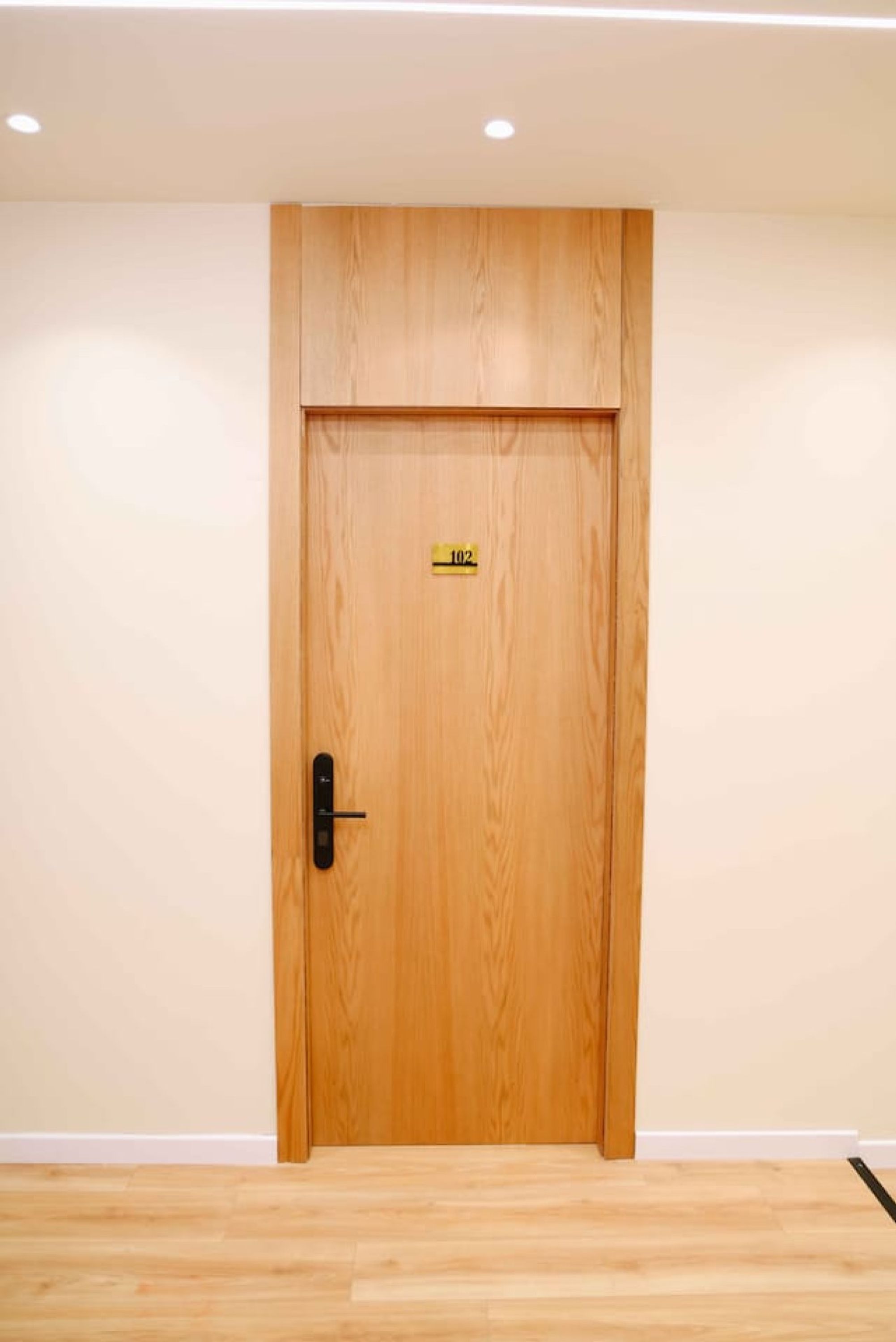 A wooden door with a number plate, a handle, and a keyhole.