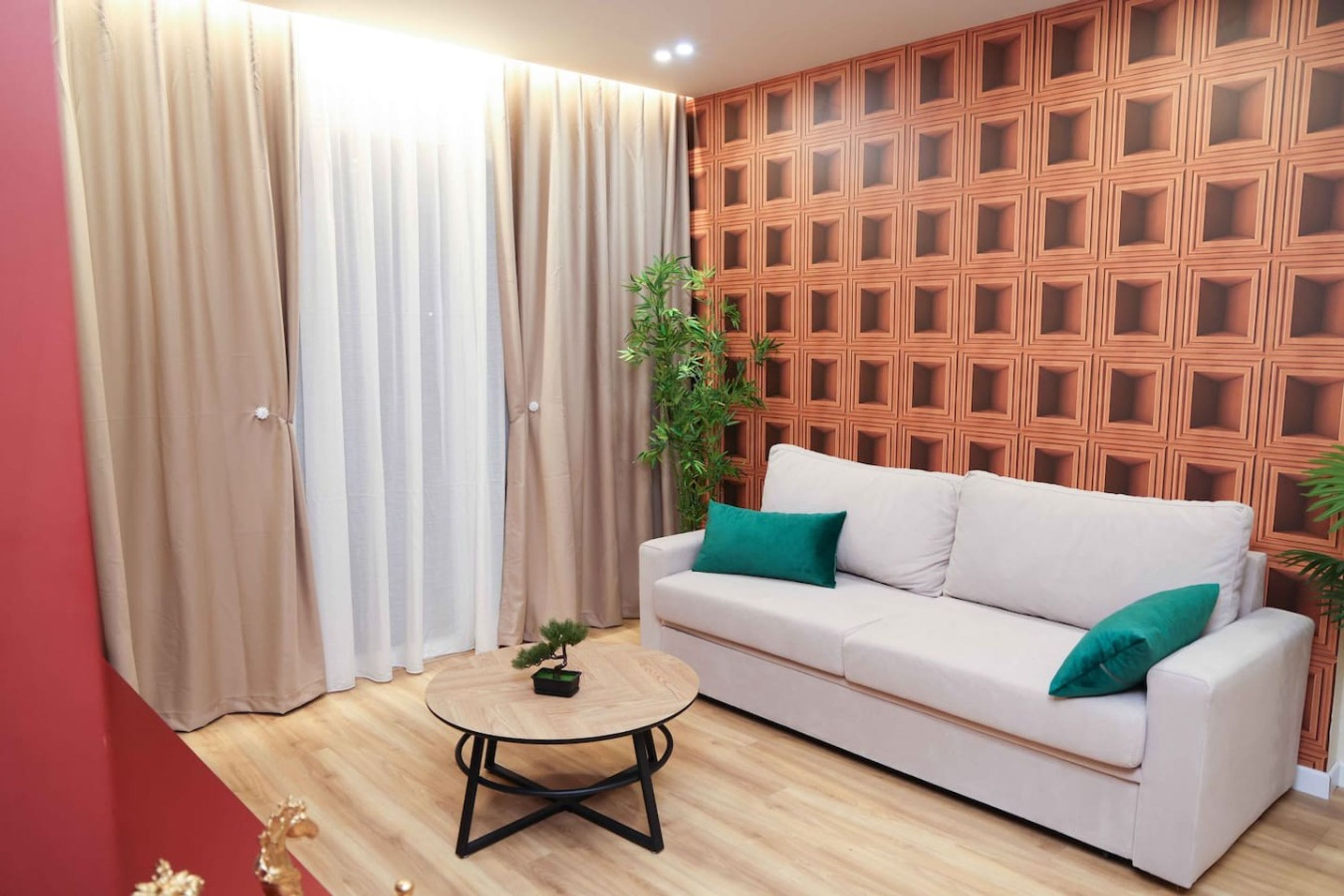 A living room with a white sofa, green cushions, a round coffee table, and a wooden wall panel.