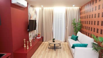 A modern living room with a red cabinet, a white sofa, a round coffee table, and a TV mounted on the wall.