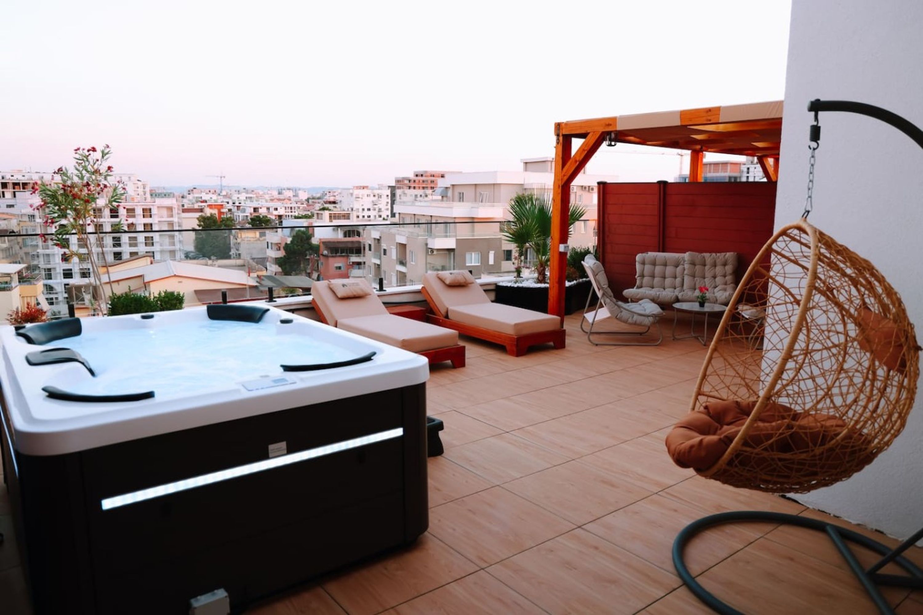 Een dakterras met een jacuzzi, lounge fauteuils en een hangstoel.
