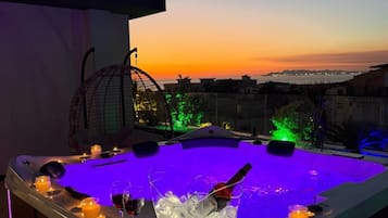A hot tub with ice and candles, set against a sunset view.