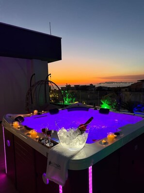 Ein Whirlpool mit Eiswürfeln und Kerzen, vor einer Sonnenlandschaft.