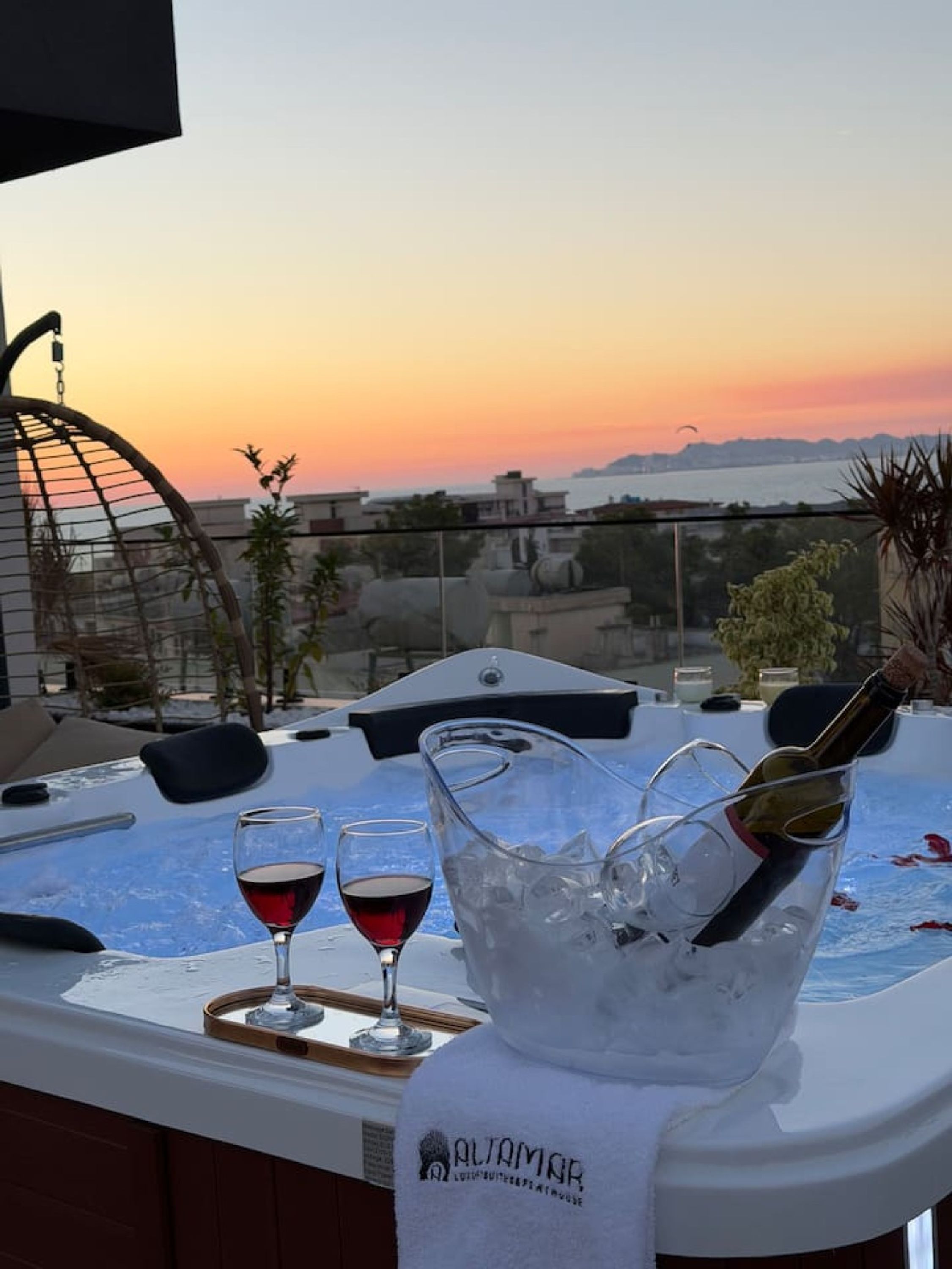 Terraza en la azotea con un jacuzzi, dos copas de vino tinto y una botella de champán en un cubo.