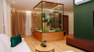 A modern living room with a glass partition, a sofa, a small table, and a green plant.