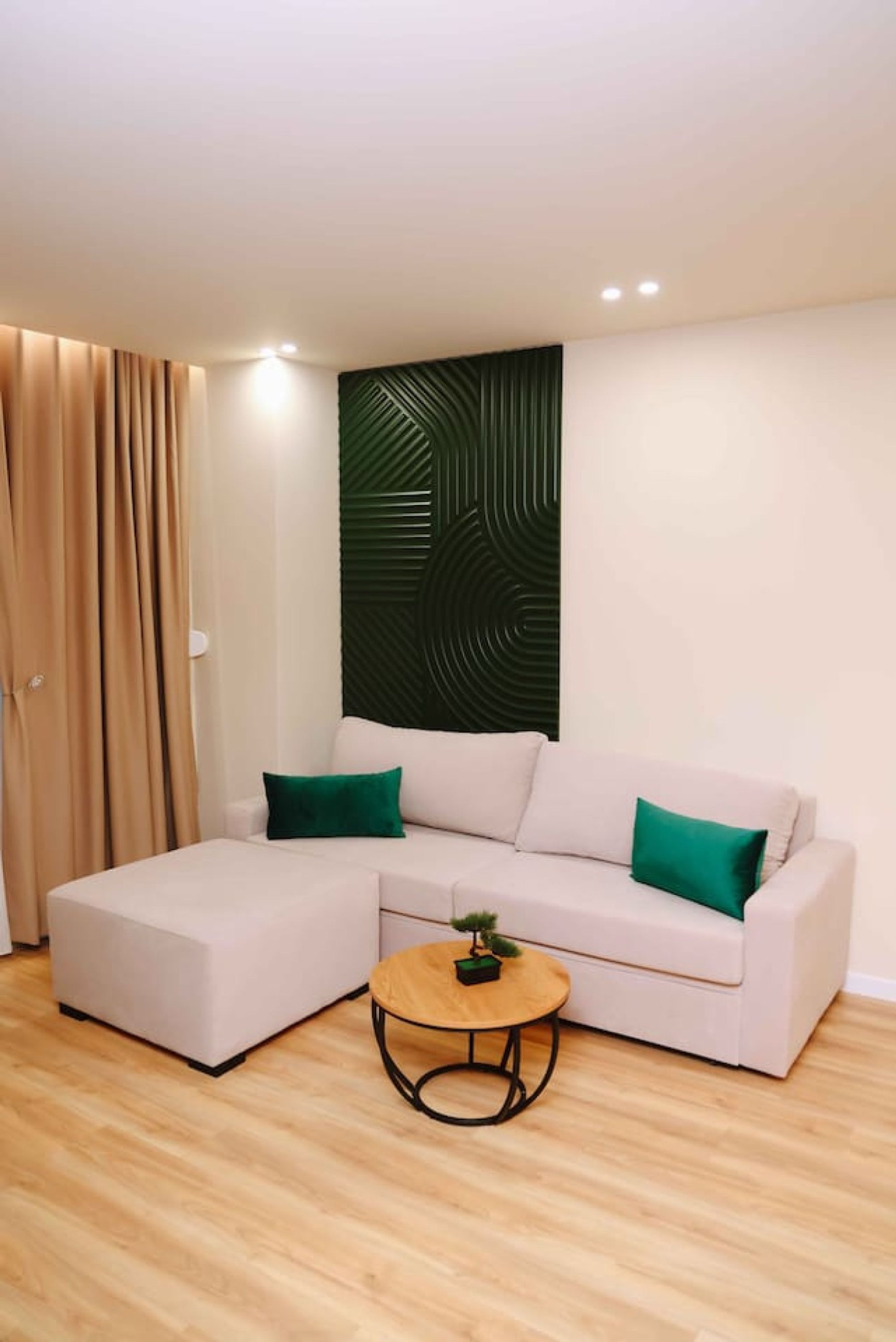 A modern living room with a sectional sofa, a small round table, and a decorative wall panel.