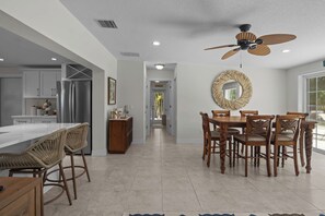 Eine moderne Küche mit Essbereich, ausgestattet mit einer großen Kochinsel, Holzstühlen und einem Deckenventilator.