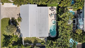 An aerial view of a resort with a swimming pool, lounge area, and palm trees. - Lucky 307- 3 bedroom with pool and spa- Managed by Beach House Real Estate (Holmes Beach)