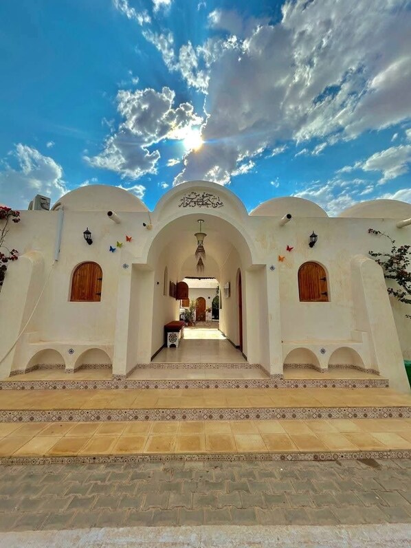 A traditional building with arched doorways, a tiled entrance, and a clear sky.