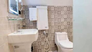 Un baño con un lavamanos blanco, un inodoro y un espejo. El suelo presenta un diseño de mármol.
