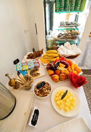 A buffet table with various food items including fruits, nuts, and pastries.