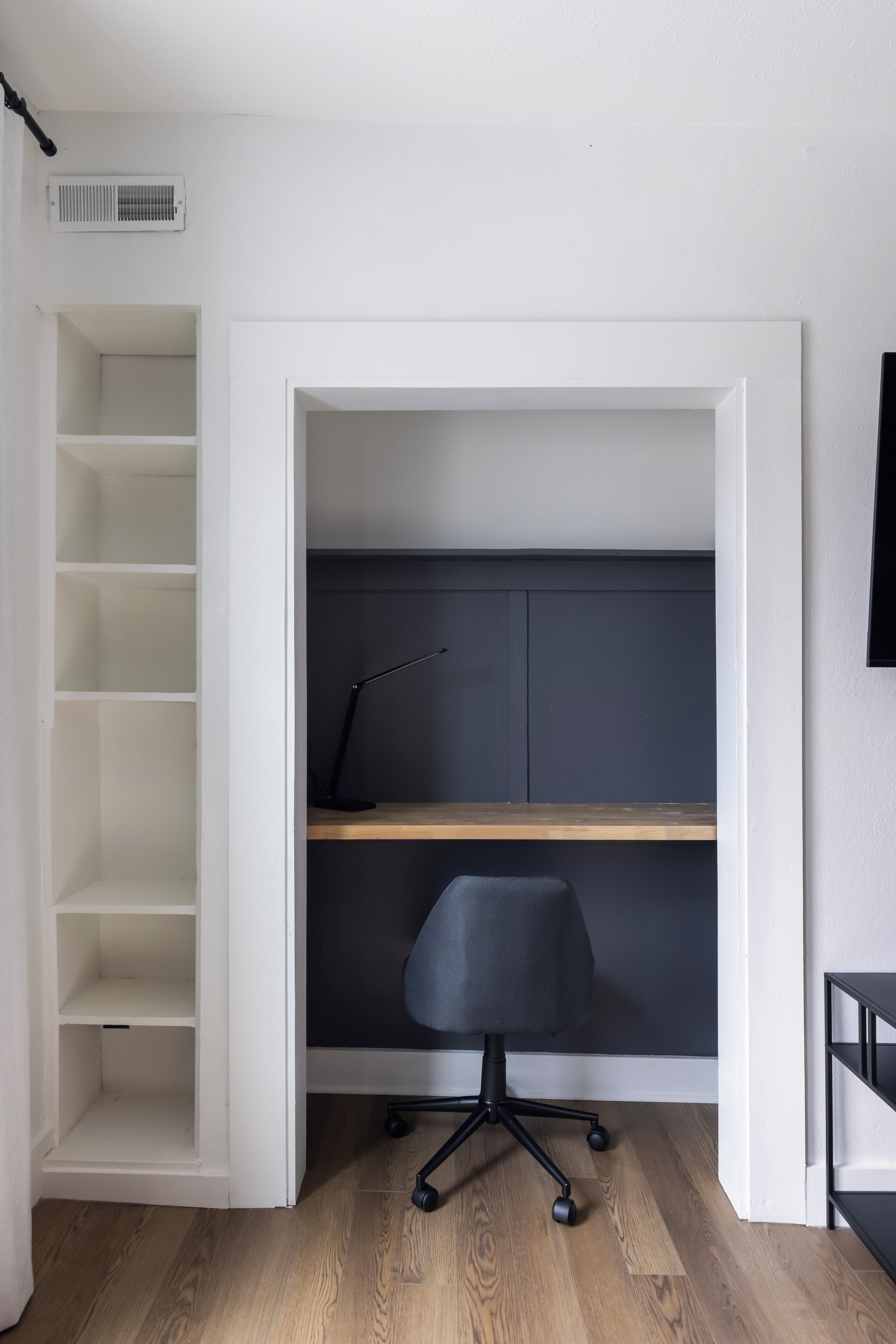 A compact office space with a desk, chair, and shelving units.