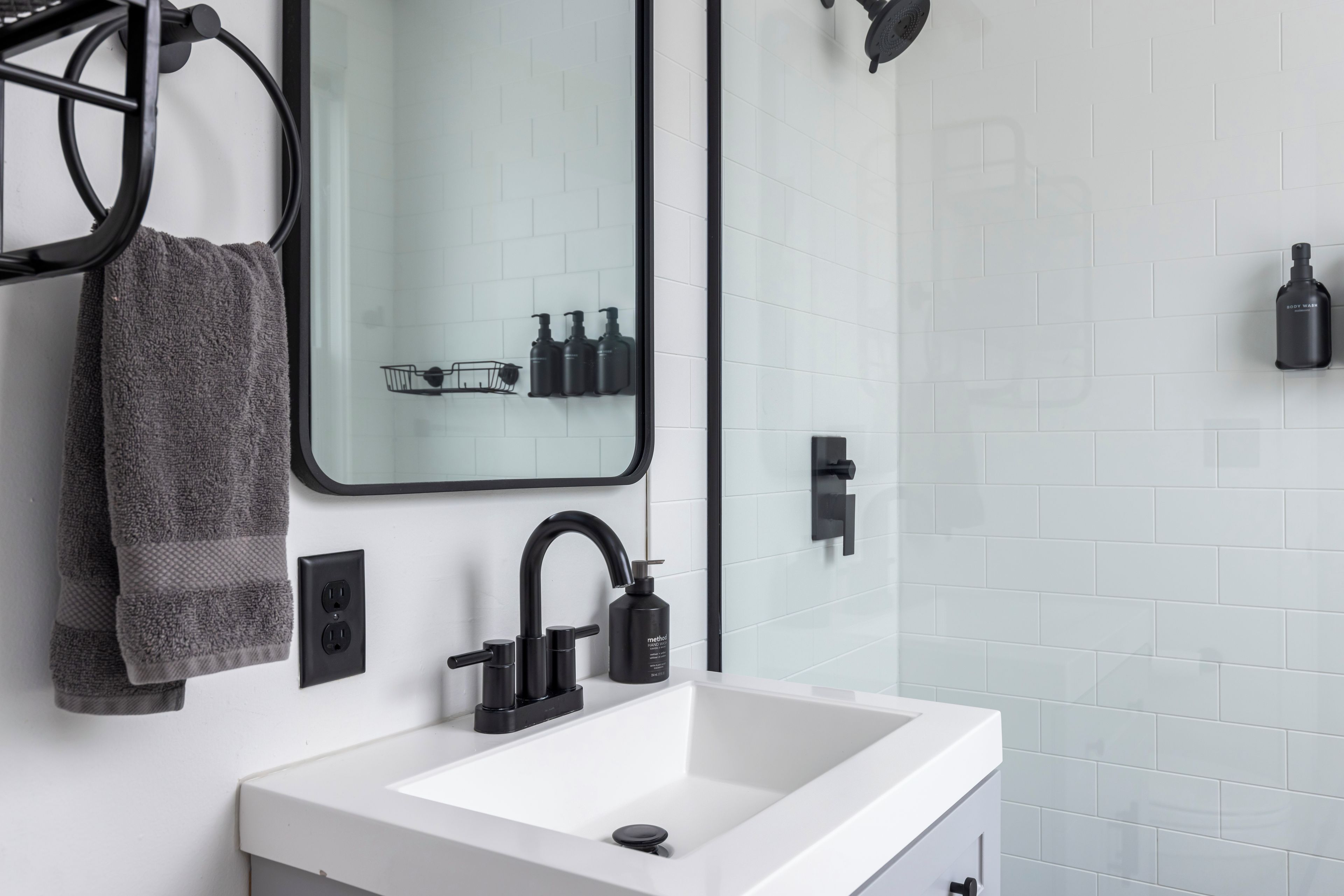 Un baño moderno con un lavabo blanco, un grifo negro y un espejo encima.
