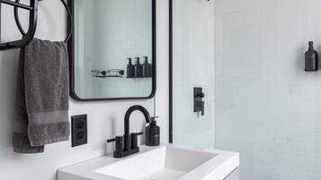 Un baño moderno con un lavabo blanco, un grifo negro y un espejo encima.