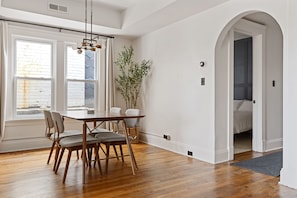 Un comedor con una mesa y sillas de madera, una lámpara colgante y una planta en maceta.