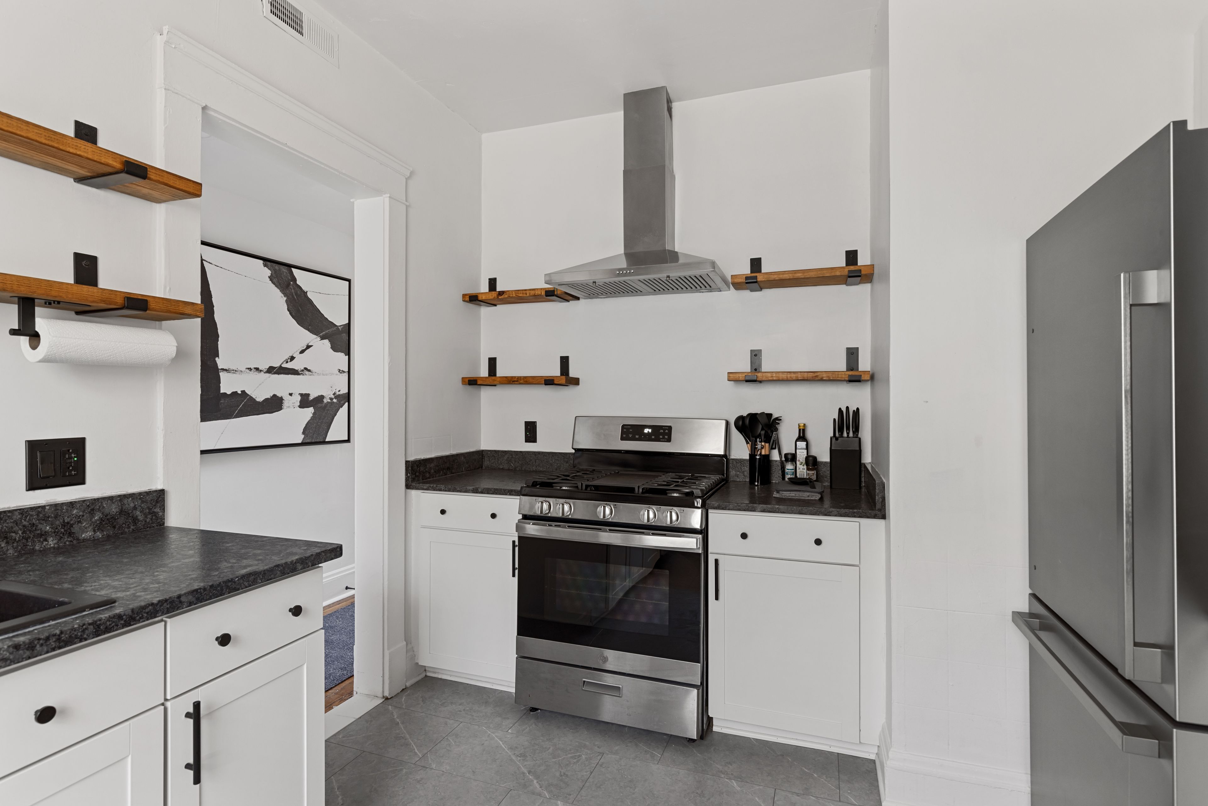 A modern kitchen with white cabinetry, a stainless steel stove, and a built-in oven.