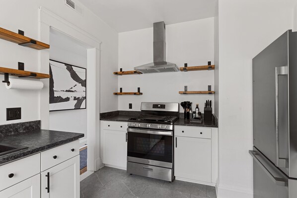 A modern kitchen with white cabinetry, a stainless steel stove, and a built-in oven.