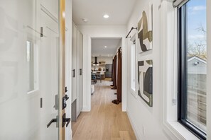 Un pasillo con puertas de vidrio, piso de madera y vista a un comedor.