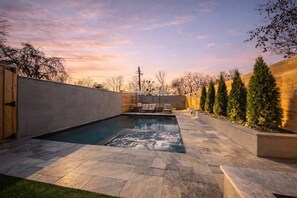 A swimming pool with a hot tub, surrounded by stone tiles and a wooden fence. - Nashville home with game room and home theater! (Nashville)