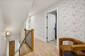 A modern interior with a wooden staircase, geometric patterned wallpaper, and a wooden chair. - Nashville home with game room and home theater! (Nashville)