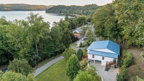A house with a blue roof, surrounded by dense forest, near a body of water. - Lake Views, Soaking Tub, Ping Pong Table, Firepit (Sharps Chapel)