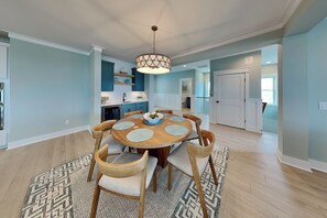 A dining area with a round wooden table, six chairs, and a patterned rug. - Klose Enough (Kure Beach)