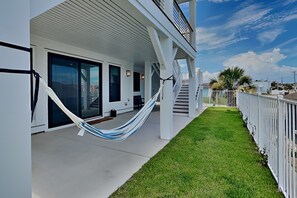 A modern building with a covered porch, a hammock, and a well-maintained lawn. - Klose Enough (Kure Beach)