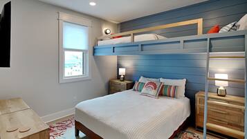 A bedroom with a bunk bed, a bedside table with a lamp, a window with blinds, and a wall clock.