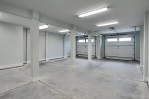 A spacious, empty garage with concrete floors and white walls, featuring multiple garage doors and overhead fluorescent lighting. - Klose Enough (Kure Beach)