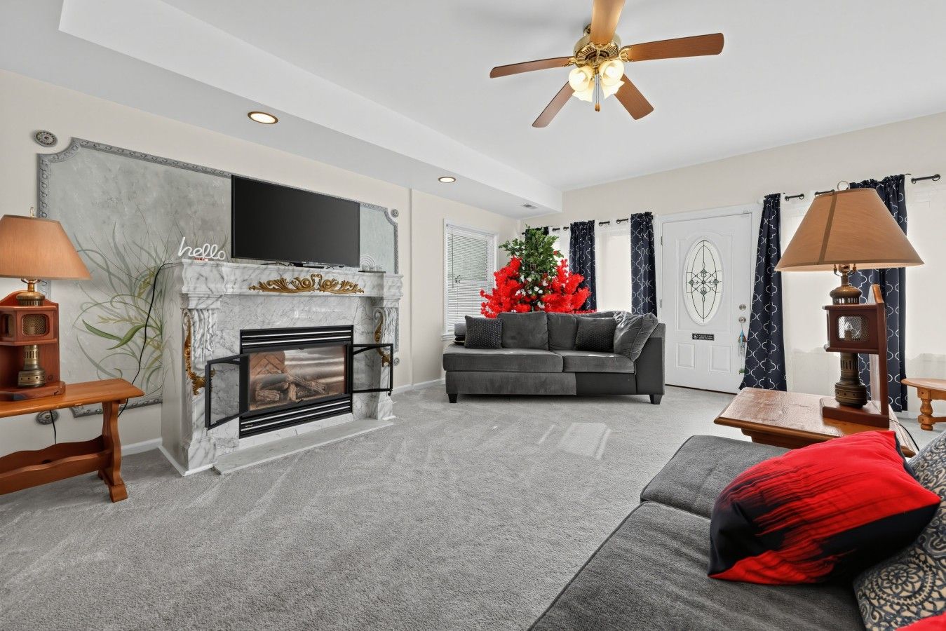 A living room with a fireplace, a sofa, a television, and a ceiling fan.