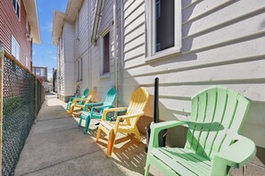 Eine Reihe bunter Adirondack-Stühle vor einem weißen Gebäude mit einem schmalen Bürgersteig.