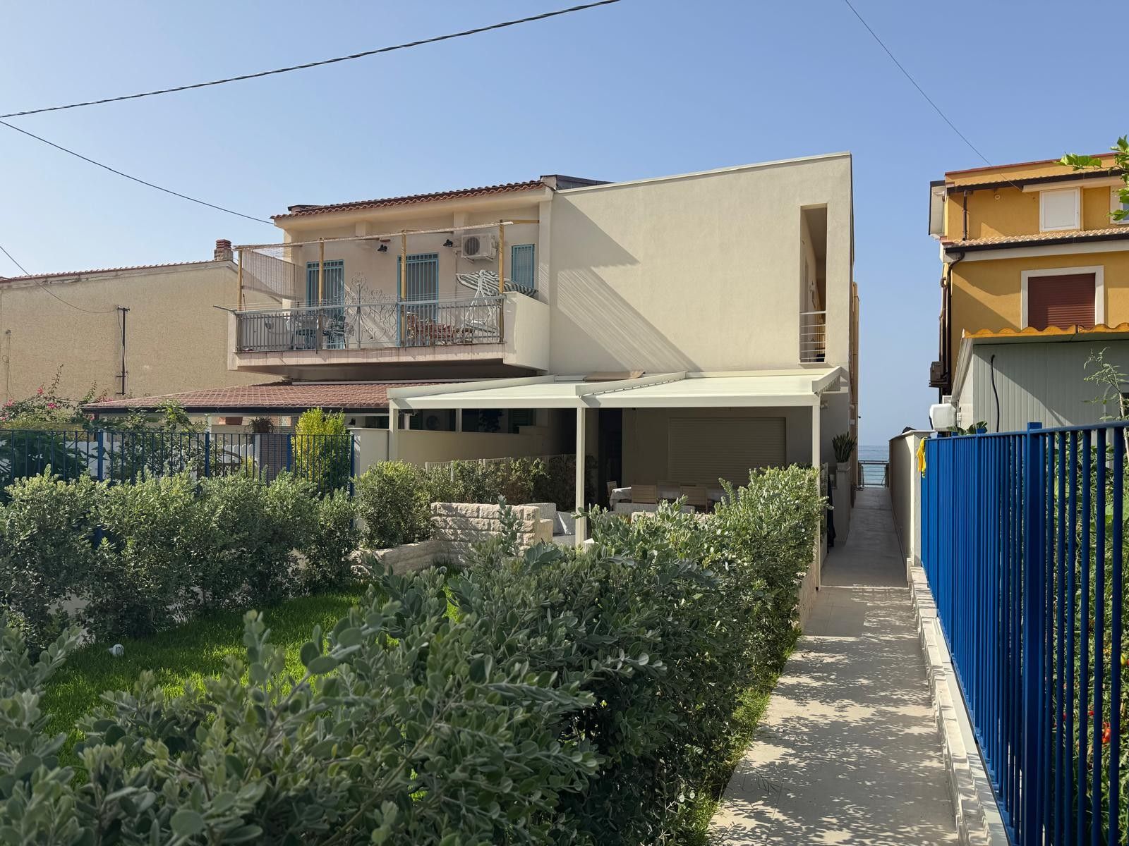 Une maison moderne à deux étages, dotée d’un patio couvert et d’un garage apparent.