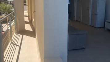 Un pasillo con balcón, refrigerador y sofá.
