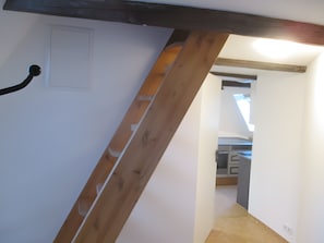 Una escalera con vigas de madera y una puerta blanca.