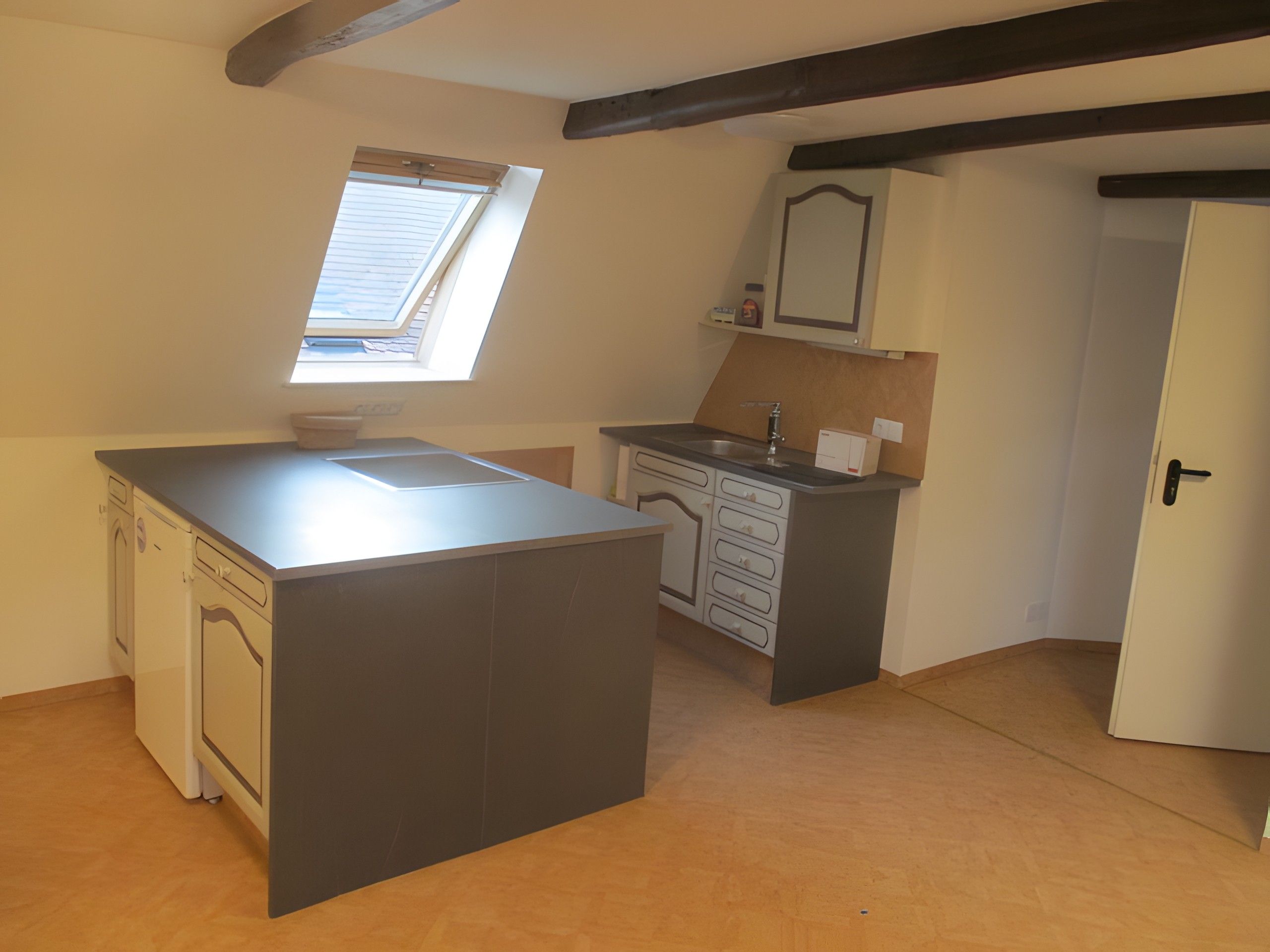 Una cocina compacta con una isla central, un ventanal y un horno empotrado.