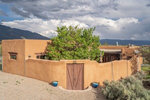 A building with a curved wall, a wooden door, and a tree in front. - Casa Lobo in Arroyo Seco (El Prado)
