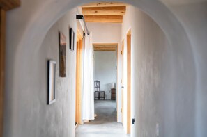 A hallway with a wooden ceiling, white walls, and framed pictures. - Casa Lobo in Arroyo Seco (El Prado)