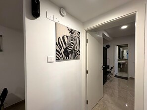 Een gang met een wanddecoratie van een zebra, een deur naar een badkamer en een stoel in de hoek.