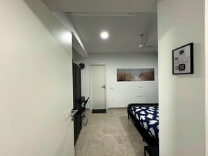 Een slaapkamer met een bed, een plafondventilator, een deur en een aan de muur bevestigd schilderij.