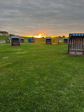 A grassy field with several small, striped, wooden structures. - Holiday Home '"Marschenhuus"' with Wi-Fi (Butjadingen)