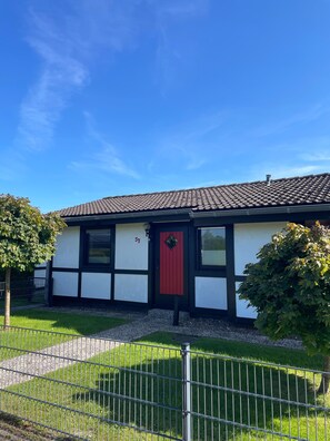 A house with a red door, white walls, and a tiled roof. - Holiday Home '"Marschenhuus"' with Wi-Fi (Butjadingen)