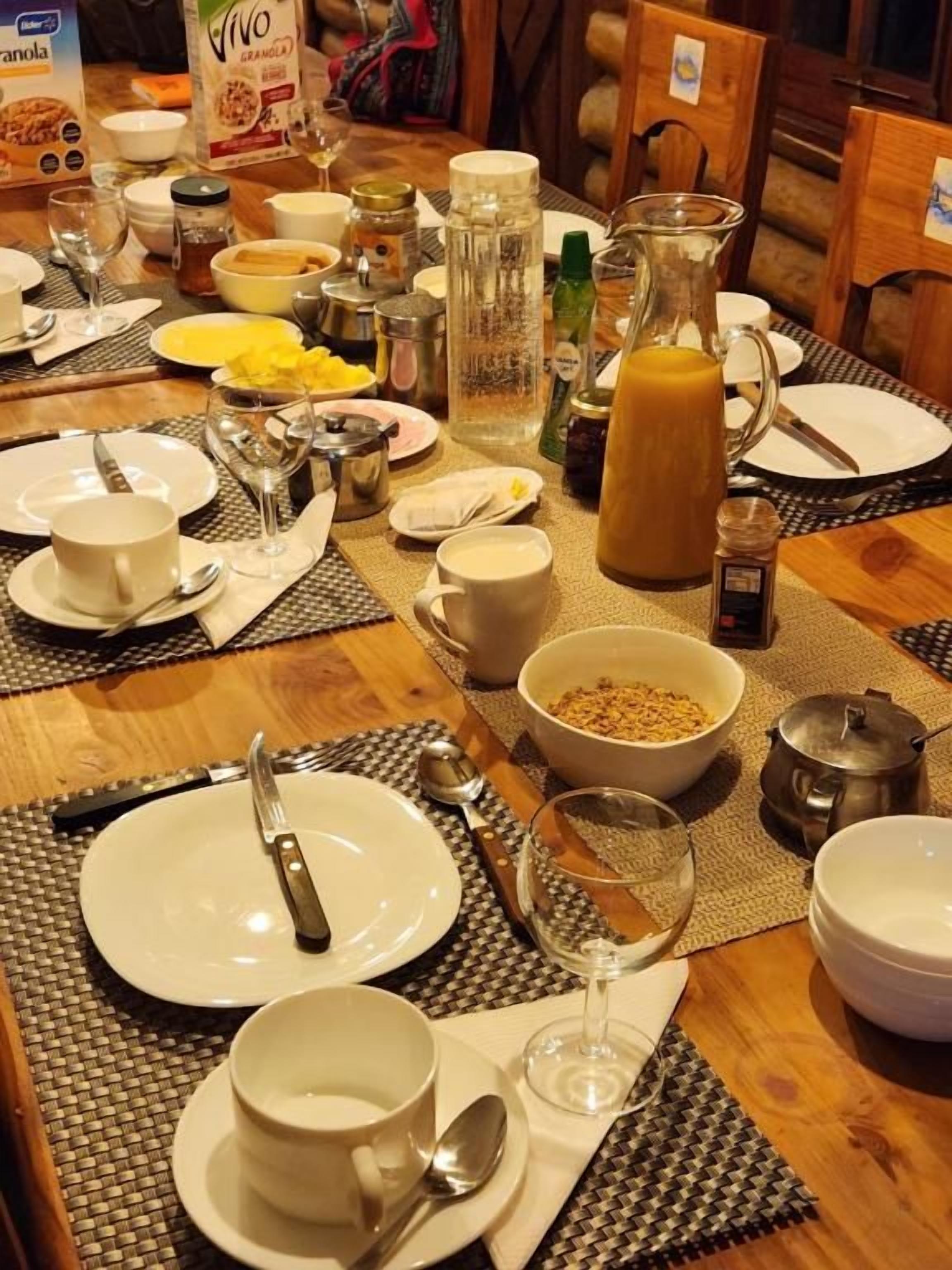 A breakfast table set with plates, bowls, cups, and a pitcher of orange juice.