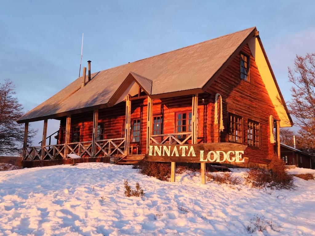 A wooden lodge with a prominent sign reading 'INNATA LODGE' in front.